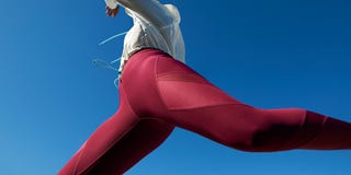 woman jumping in red leggings against blue sky
