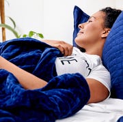 woman lying in bed with blue gravity blanket and pillows