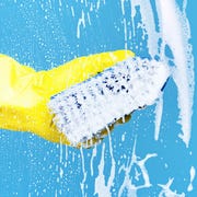 hand in yellow rubber glove using blue scrub brush