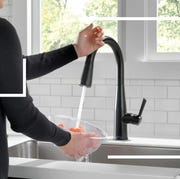 woman holding hand up to kitchen smart faucet