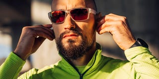 runner in polarized sport sunglasses putting earbuds in ear